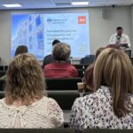 The audience facing a screen with a speaker welcoming them at the start of the Jisc event.