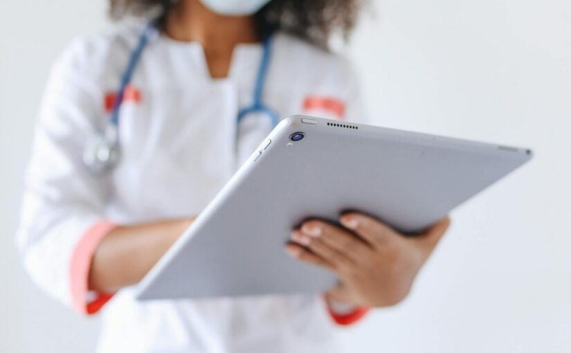 person wearing a face mask holding an ipad