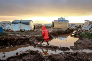 unrecognizable girl walking on mud against poor houses