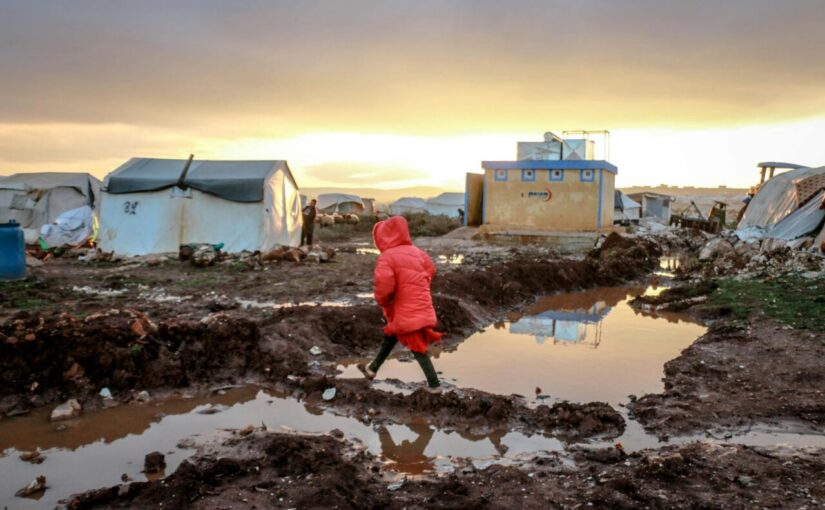 unrecognizable girl walking on mud against poor houses