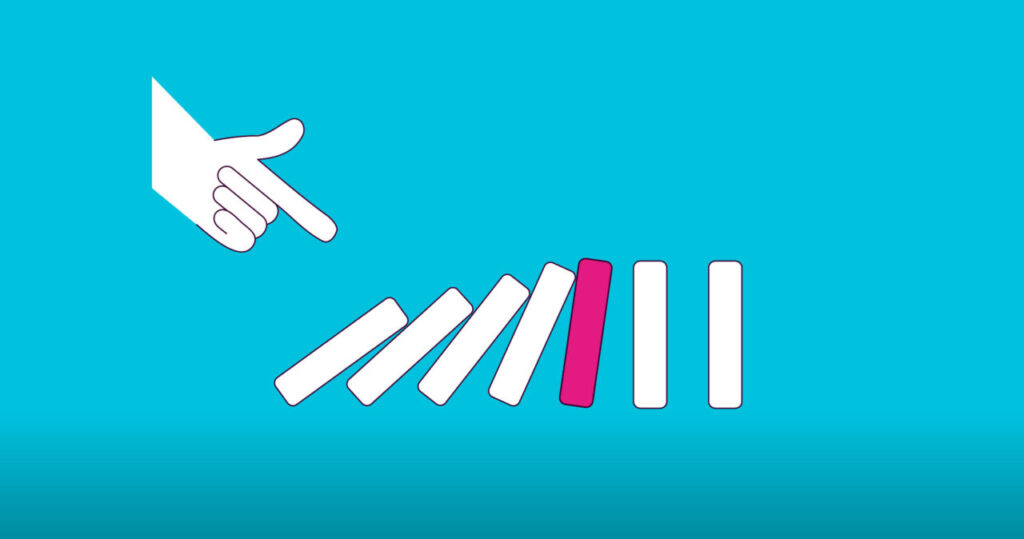 A hand top left points towards a row of domino pieces fallen into each other.