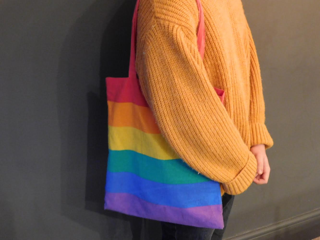Person with a pride flag tote bag